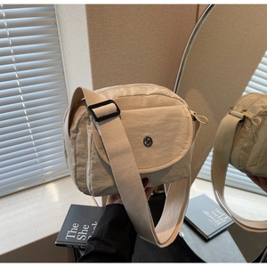 Nahaufnahme einer beige Nylon Umhängetasche mit breitem Gurt und Logo-Detail