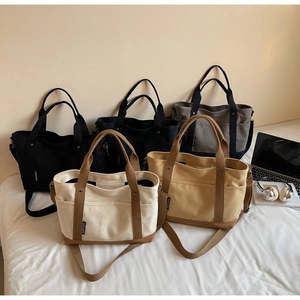 Multiple functional canvas tote bags in various colors displayed on a bed for daily use