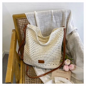 Detailed close-up of white crochet texture and brown leather strap on woven tote bag