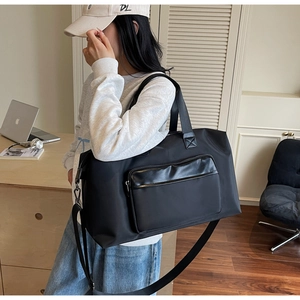 Large black travel bag with waterproof nylon texture and detachable strap on male model