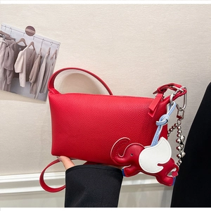 Dettaglio borsa rossa in pelle a grana con ciondolo a elefante e catena in metallo