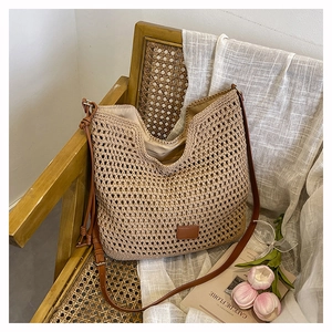Close-up of woven straw tote bag with brown leather strap on a rustic chair with tulips