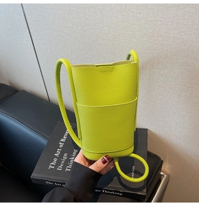 Detail of neon green bucket bag featuring a premium lychee texture and thin strap