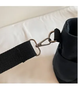 Close-up of durable metal swivel hooks and reinforced stitching on black canvas tote bag