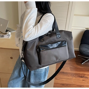 Close-up of a large dark brown travel bag with leather accents and black straps