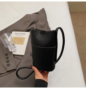 Detail of black lychee grain leather bucket bag with slim shoulder strap and front pocket