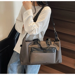 Side view of a large travel bag with dual handles and adjustable shoulder strap on stairs