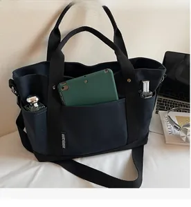 Detail of black canvas tote bag showing spacious interior with tablet and daily essentials
