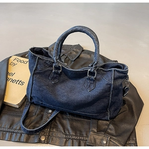 Détail d'un cabas en jean vintage bleu marine avec bords effilochés sur cuir noir