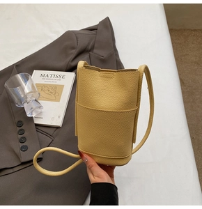 Detail of light yellow lychee pattern leather cylindrical crossbody bag with strap