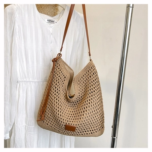 Close-up of a woven oatmeal shoulder bag with dark brown leather straps on a hanger