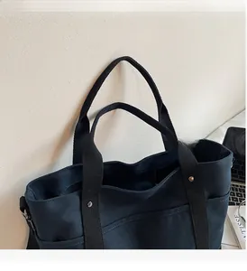 Detail of durable canvas tote bag showing reinforced metal rivets and dual handle design