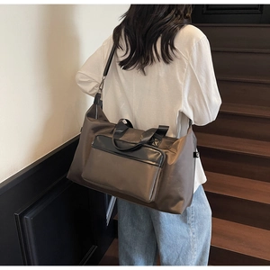 Brown waterproof nylon travel bag with black straps worn by a person on stairs