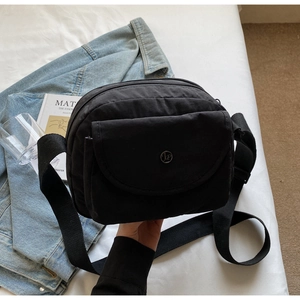 Makroaufnahme einer schwarzen Nylon-Umhängetasche mit Mehrschicht-Reißverschlüssen und Logo