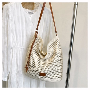 Close-up of white woven mesh shoulder bag with brown leather straps and fabric lining