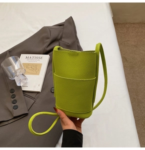 Detail of lime green pebble leather phone bucket bag with front pocket and shoulder strap