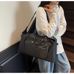 Action shot of large black travel bag with adjustable strap on a modern staircase