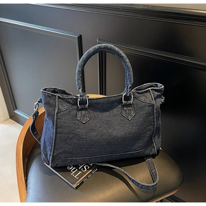 Détail du sac cabas en jean bleu avec coutures blanches et poignées rondes sur chaise