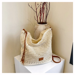 Close-up of beige hollow woven tote bag featuring brown leather straps and detail