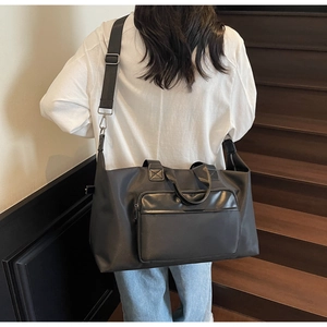 Rear view of model carrying a large black waterproof nylon travel bag on a wooden staircase