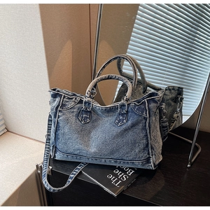 Détail d'un sac cabas en jean vintage avec texture délavée, poignées et bandoulière amovible