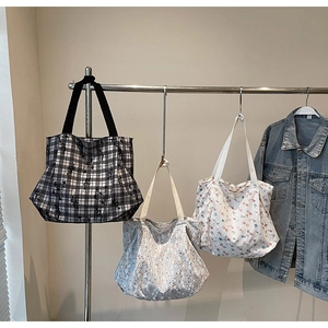 Close-up of canvas tote bags in plaid and floral patterns hanging on a metal rack
