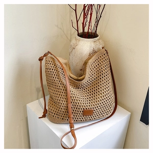 Close-up of woven straw tote bag with brown leather straps and zip lining detail