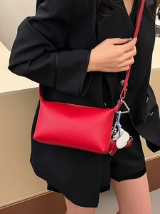 Borsa a tracolla minimalista rossa a grana di litchi con ciondoli su un blazer nero