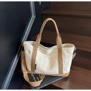 Detail of canvas tote bag showing cream and camel contrast panels with reinforced handles