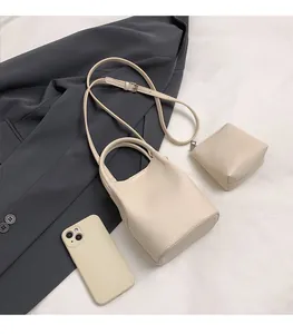 Close-up of beige lychee leather mini bucket bag with small coin purse and strap
