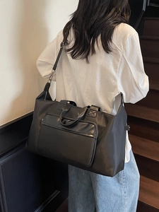 Black large capacity travel duffel bag shown on shoulder against a staircase background