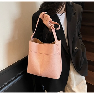 Detail of pink pebbled leather bucket bag featuring decorative stitching and sturdy handle