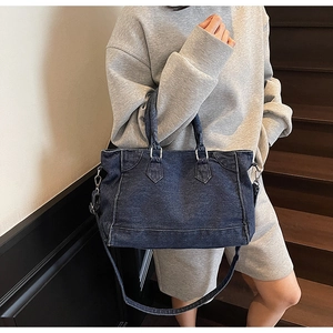 Détail d'un grand cabas en jean vintage avec surpiqûres blanches et bandoulière réglable