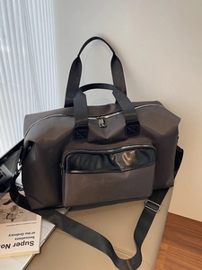 Large dark grey travel duffel bag with waterproof fabric on a leather chair in a room