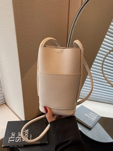 Minimalist beige lychee grain leather bucket crossbody bag with a slim strap for women