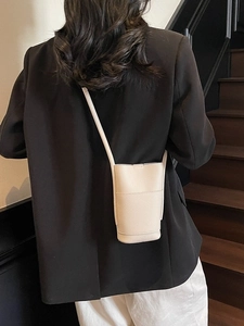 Chic cream mini crossbody bucket bag with lychee texture worn by a model in black blazer