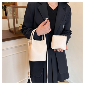 Chic beige lychee textured bucket bag and matching mini pouch shown on a model