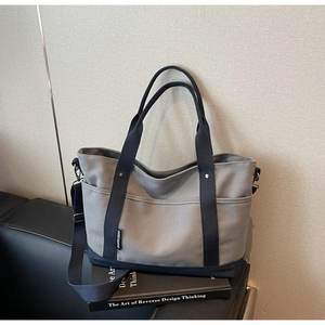 Detail of gray canvas tote bag with navy blue side pocket and adjustable shoulder strap