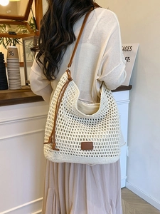 Chic beige crochet tote bag with brown leather straps shown on a model in a cafe setting