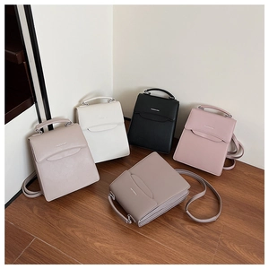 Minimalist crossbody handbags in five solid colors displayed on warm wooden flooring