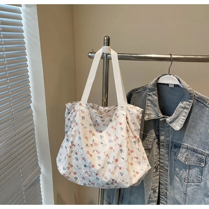 Detail of floral canvas tote bag with lace texture and wide white woven shoulder straps