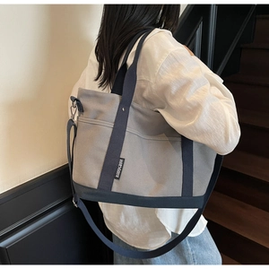 Side view of large canvas tote bag with navy straps on model in modern interior