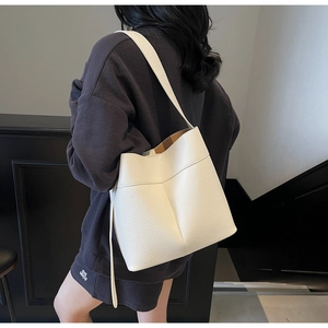 Close-up of white lychee grain leather bucket bag with wide shoulder strap on model