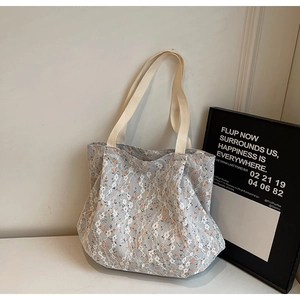 Dettaglio della borsa tote in tela floreale con pizzo bianco e manico intrecciato