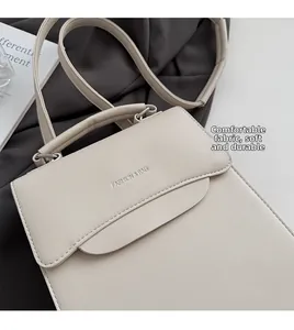 Detail view of beige PU leather handbag with silver Fashion & Bag metal logo and top handle