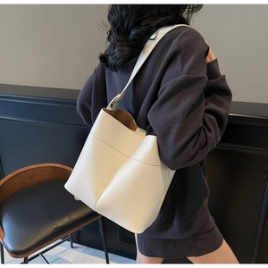 Detailed macro view of the cream leather bucket bag showing fine pebble grain texture