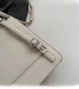 Detail of silver metal buckle and fine stitching on a cream leather shoulder bag