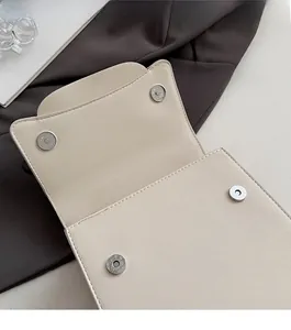 Detail of the magnetic buckle closure on a cream lychee pattern PU leather handbag