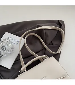 Detail of minimalist cream leather handbag showing smooth texture and slender shoulder strap