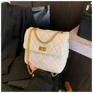 Detail of quilted diamond pattern and gold twist lock on cream chain crossbody bag